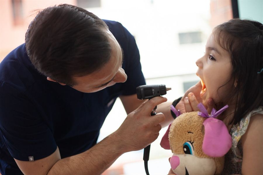 El Dr. Horacio Bartlett revisa los oídos de una niña con el otoscopio